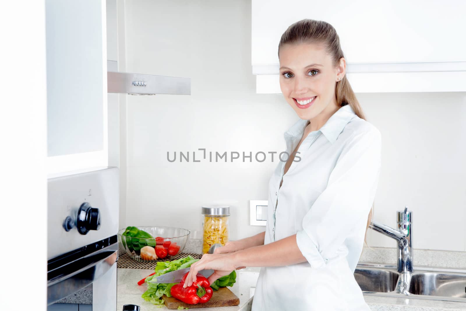 Pretty young adult female cutting vegetables in the kitchen