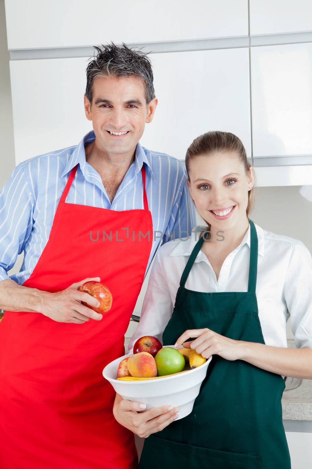 Happy couple standing in kitchen with bowl of fruit