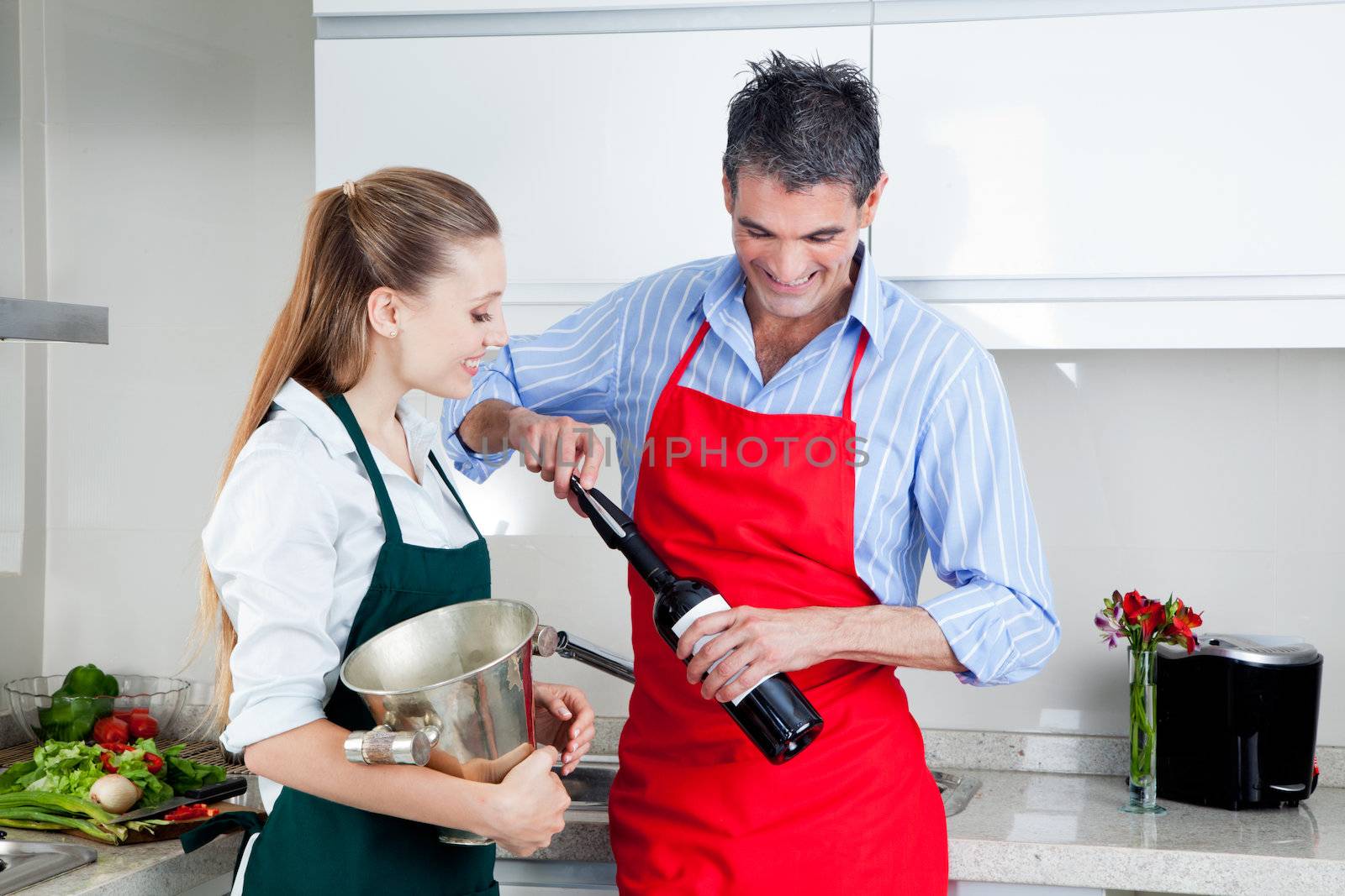Man and woman opening wine bottle at home in kitchen.