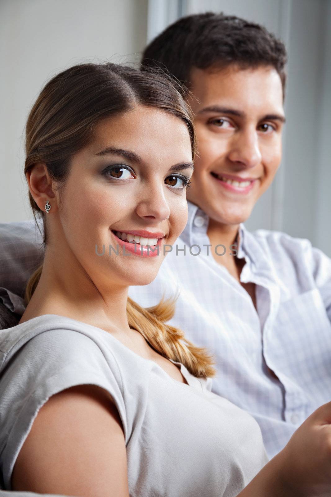 Portrait of young woman smiling while sitting besides boyfriend