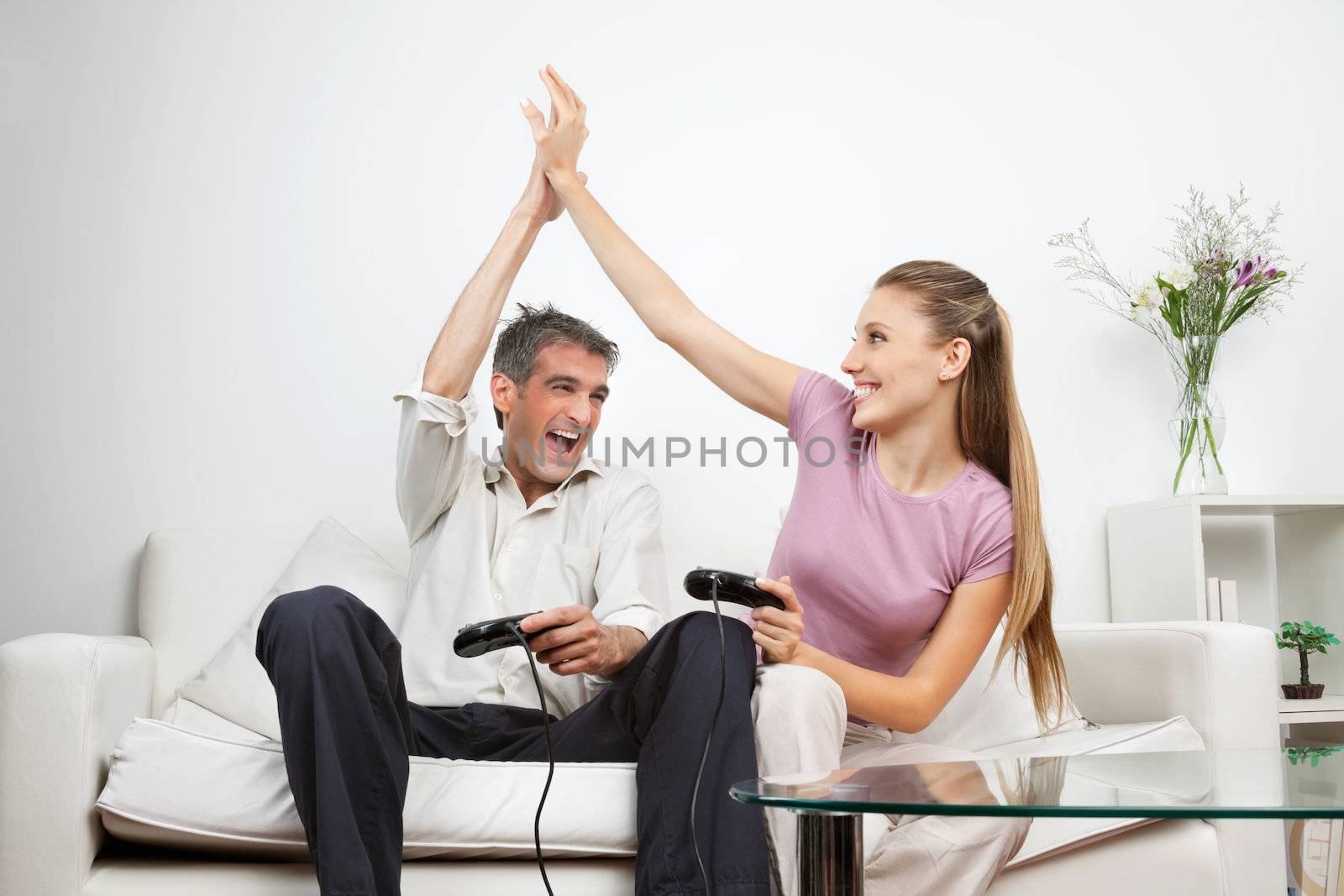 Couple giving a high-five to each other while having great time playing video game together