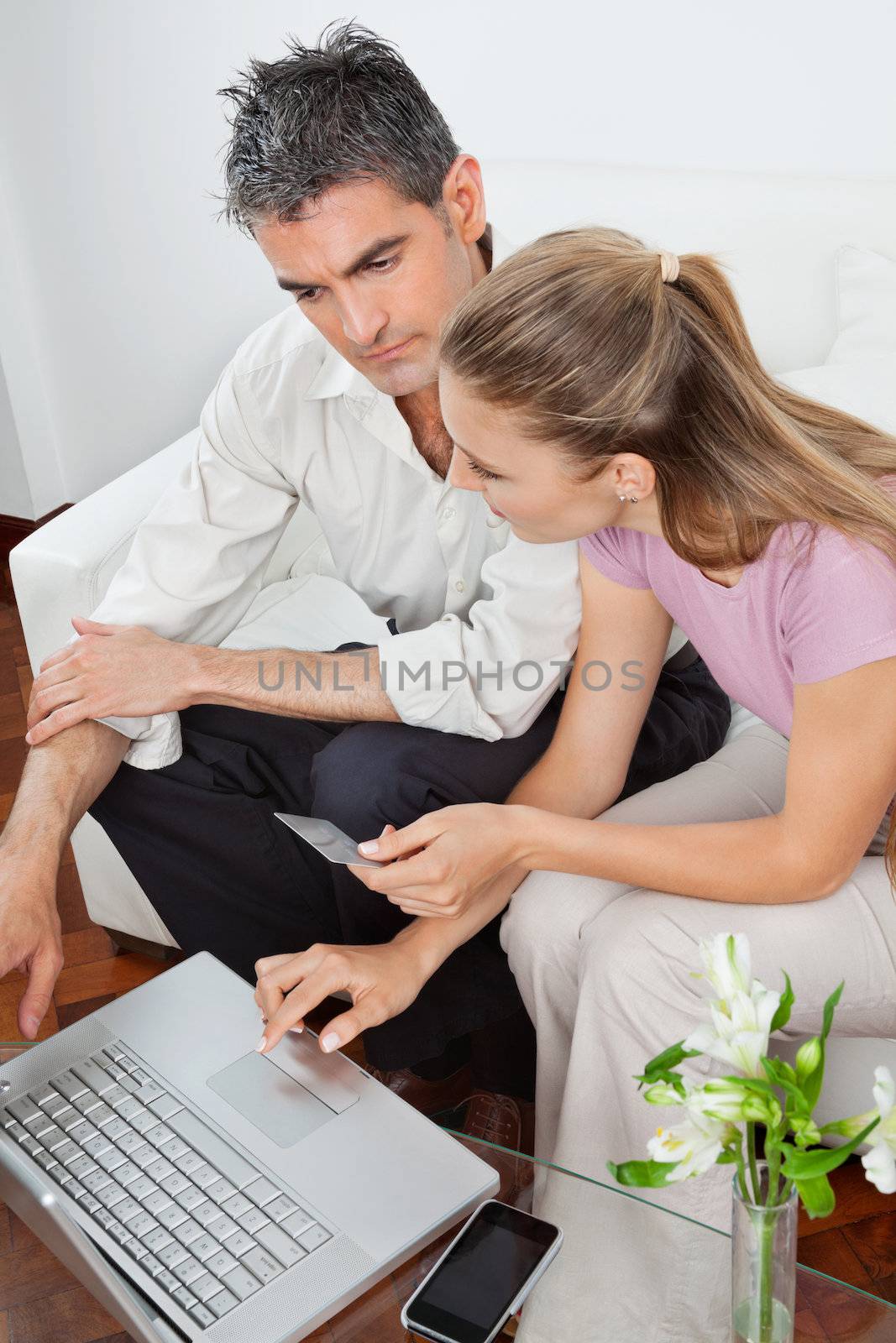 High angle view of couple with laptop using credit card for online shopping