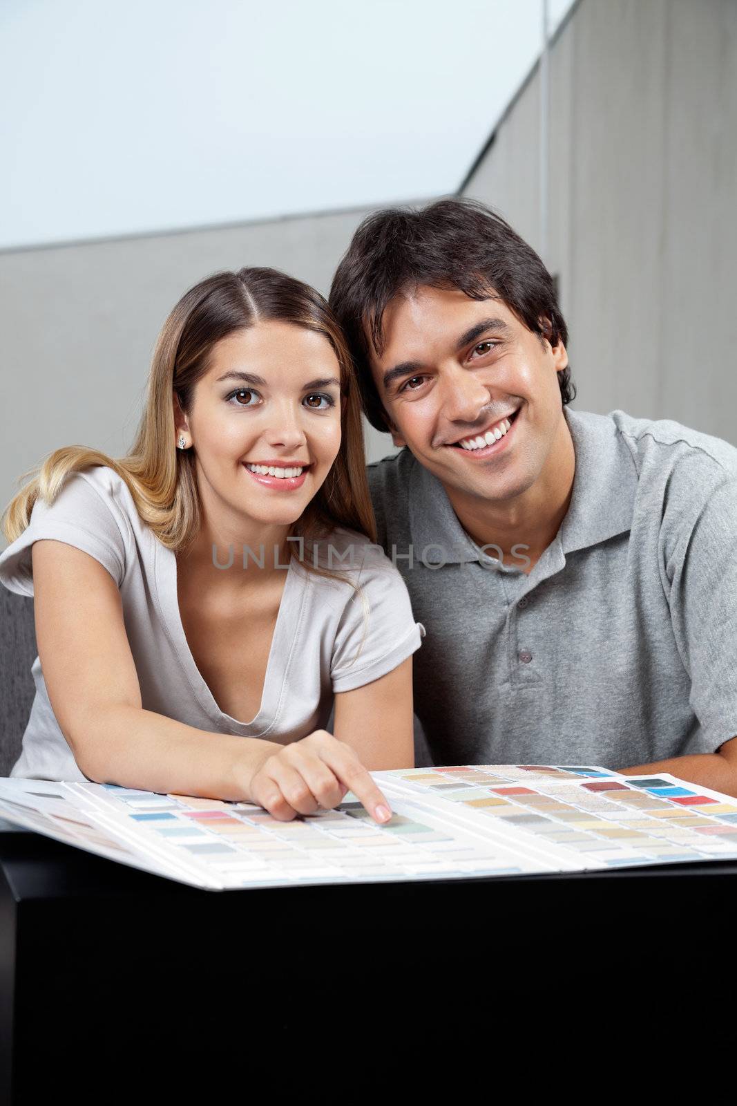 Portrait of happy young couple sitting together with color swatch chart