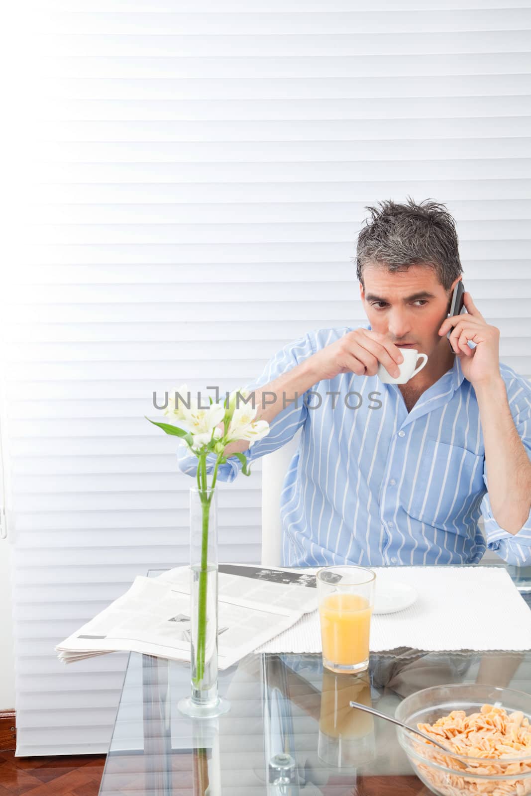 Mature man having breakfast using phone.