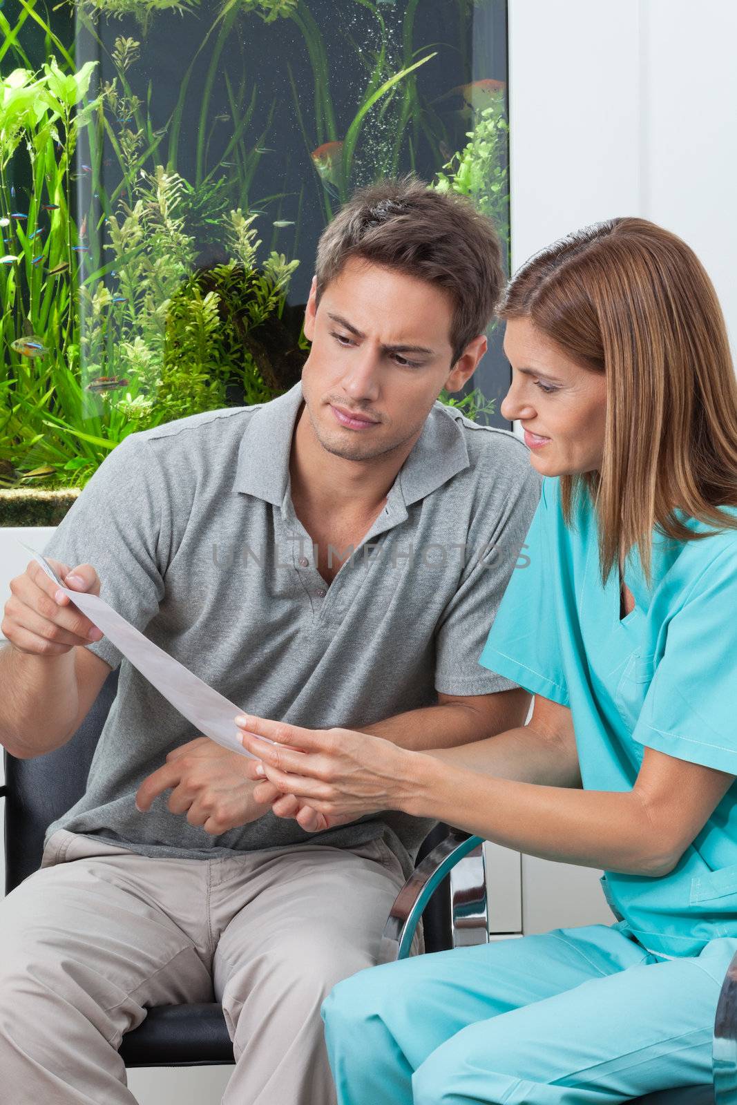 Female dentist showing report to male patient in clinic