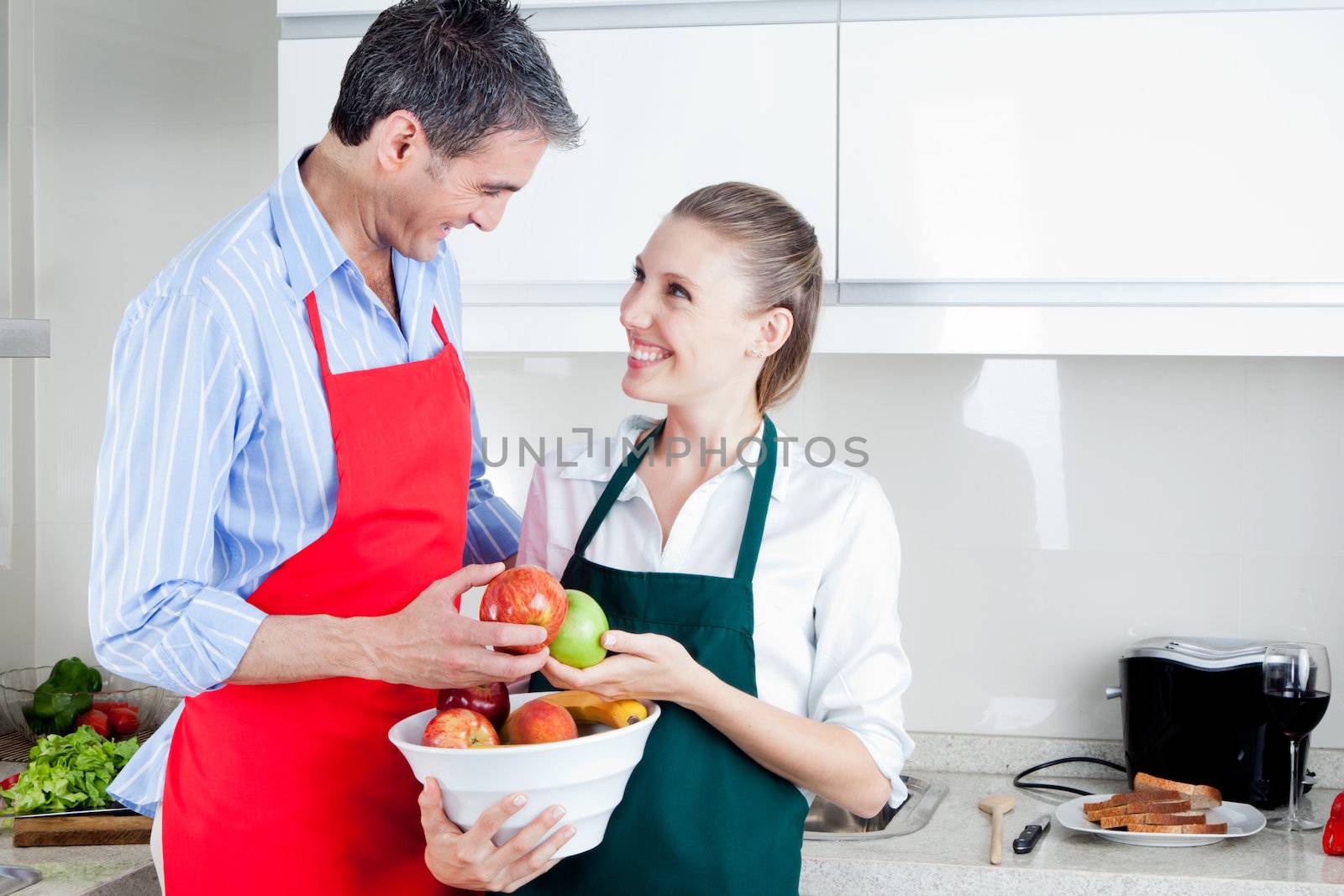 Happy middle aged couple in kitchen preparing food
