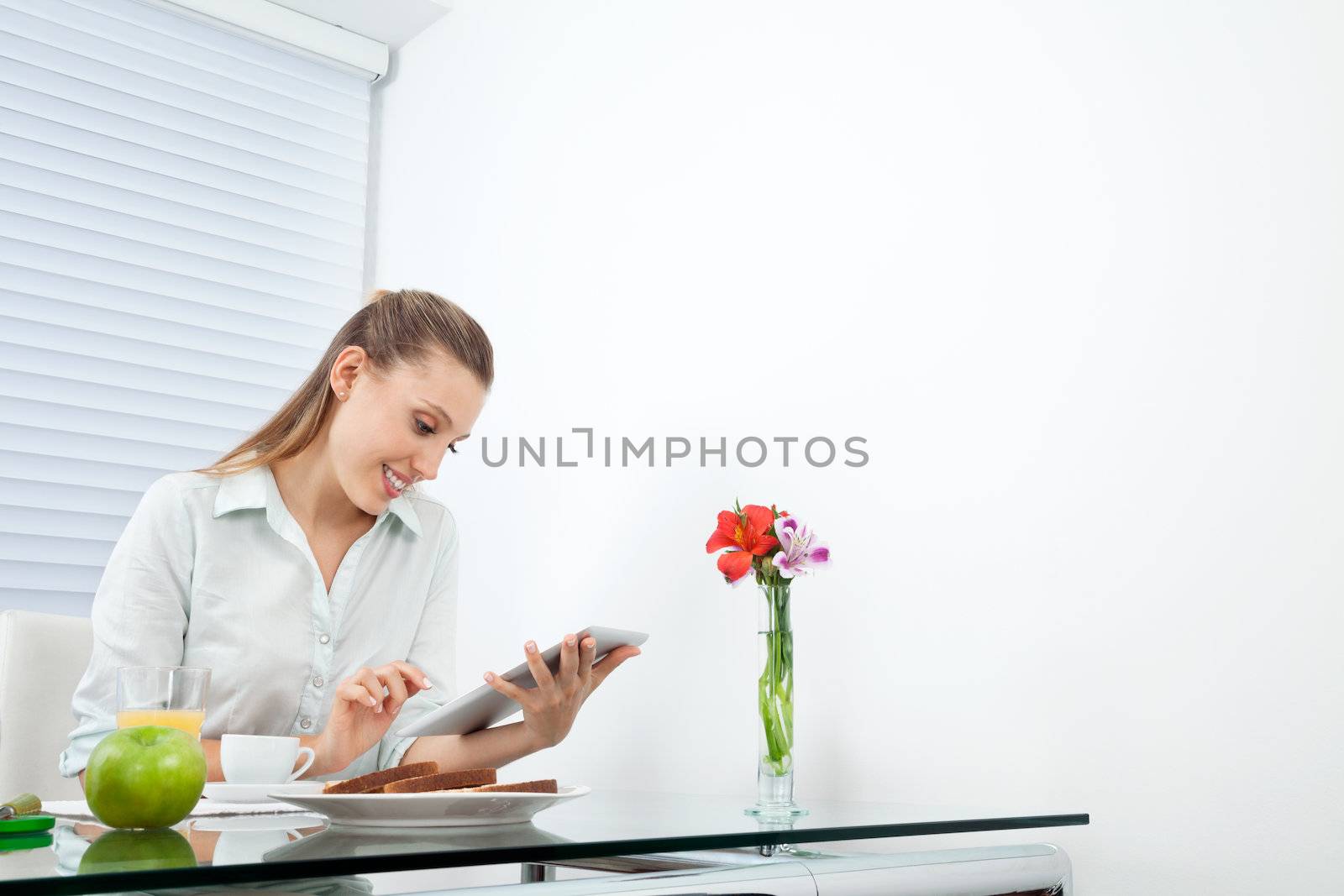 Businesswoman At Breakfast Table Using Tablet PC by leaf