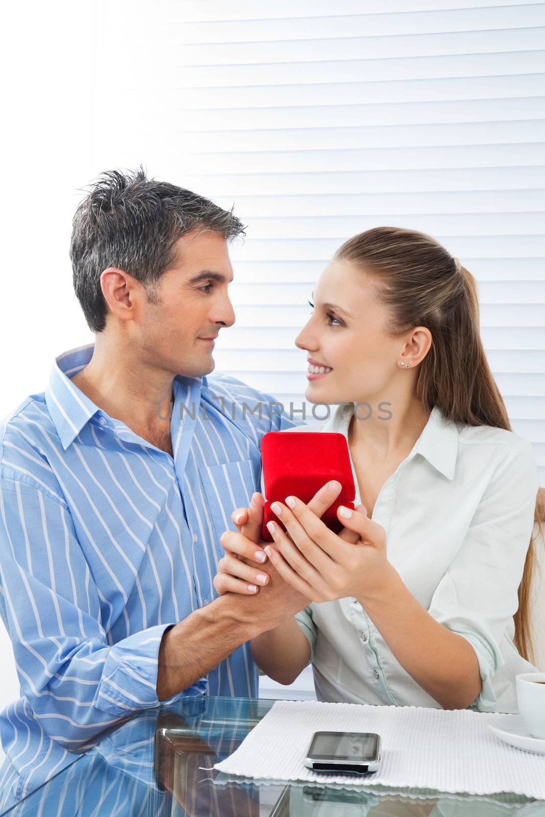 Middle aged man making proposal of marriage to beautiful woman while sitting at table