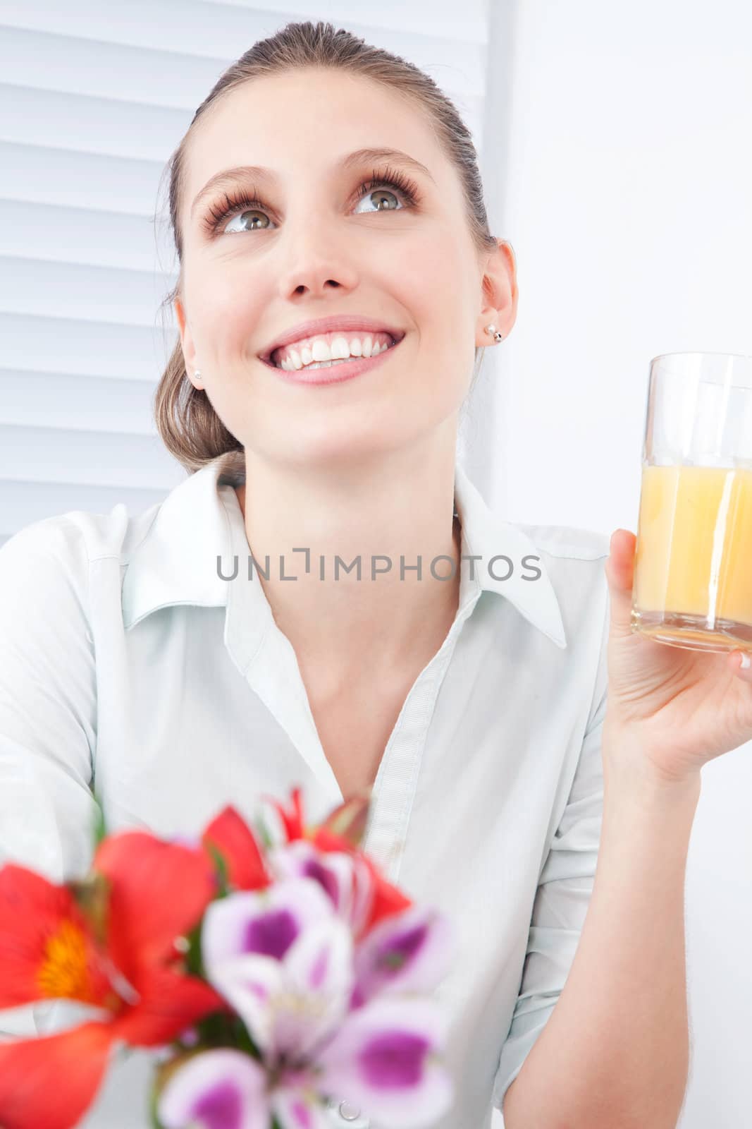 Young woman holding glass of juice, dreaming.