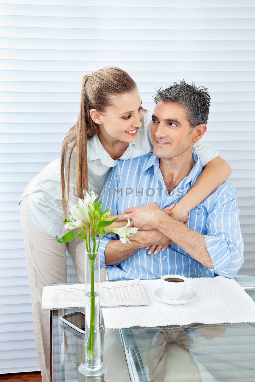Couple looking at each other while embracing by a table