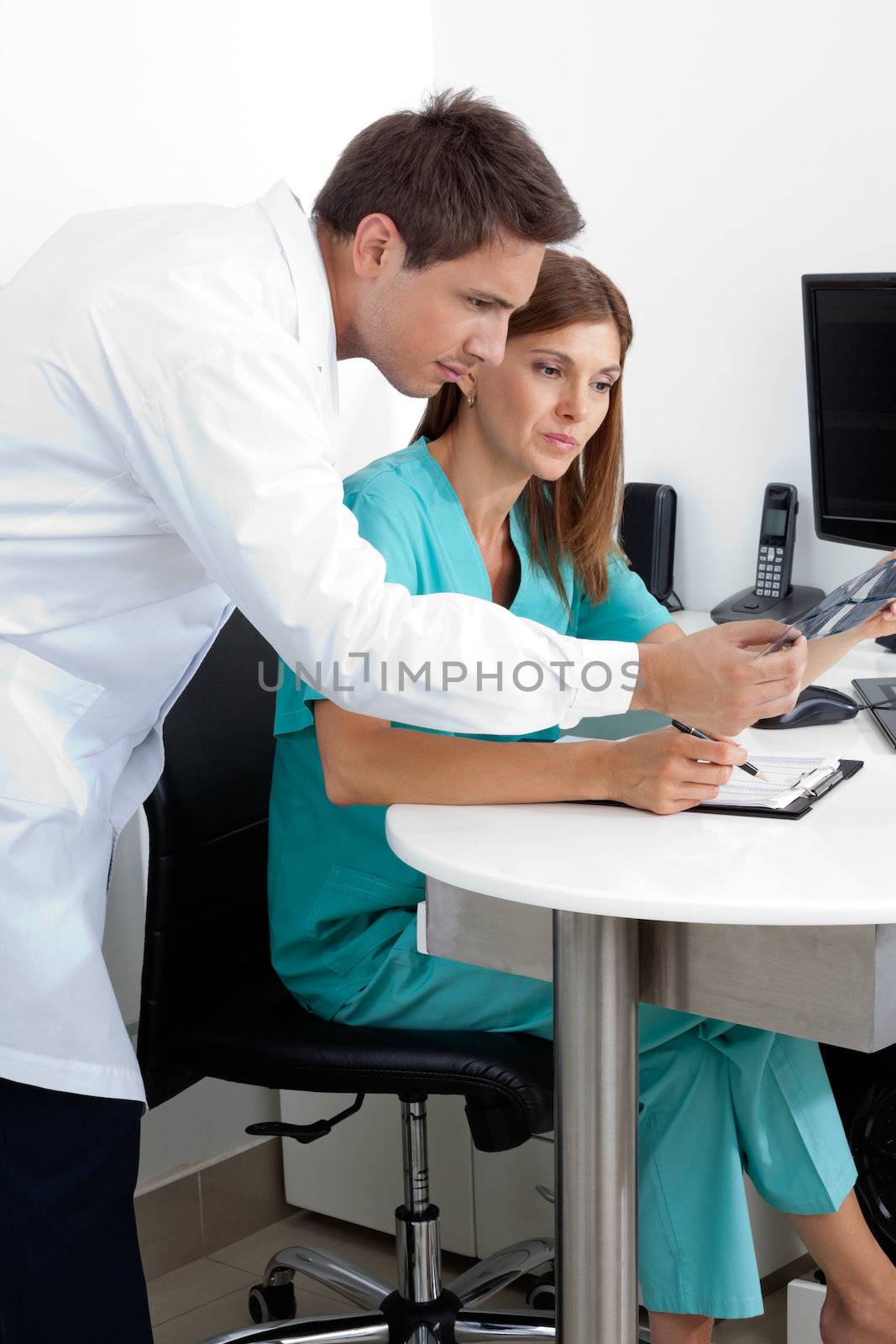 Male dentist and assistant checking X-ray at dental clinic