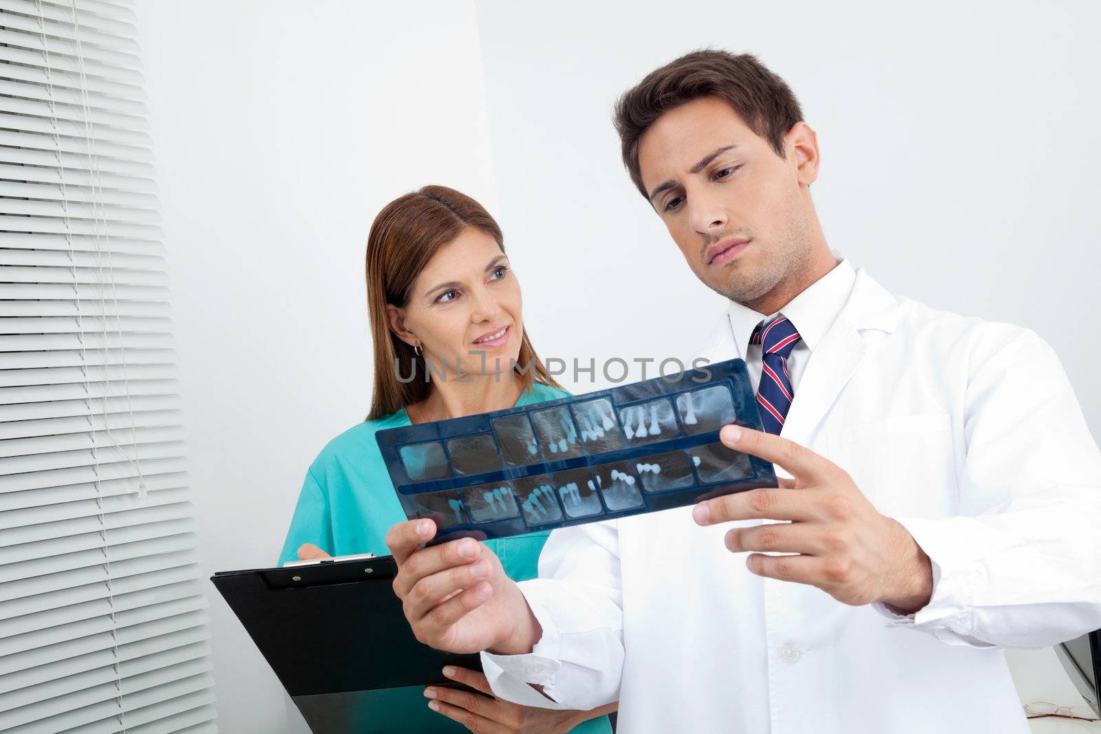 Doctor And Assistant Analyzing Patient's Report by leaf
