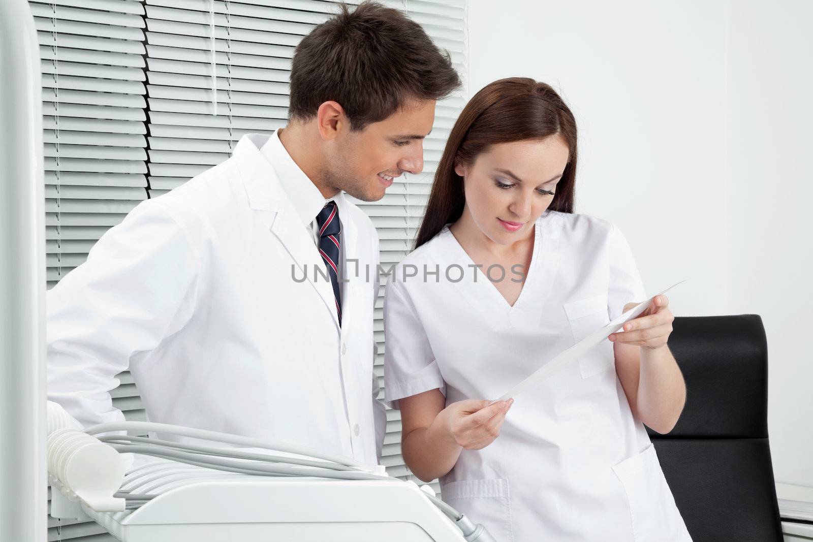 Dentist And Assistant With Dental Report by leaf