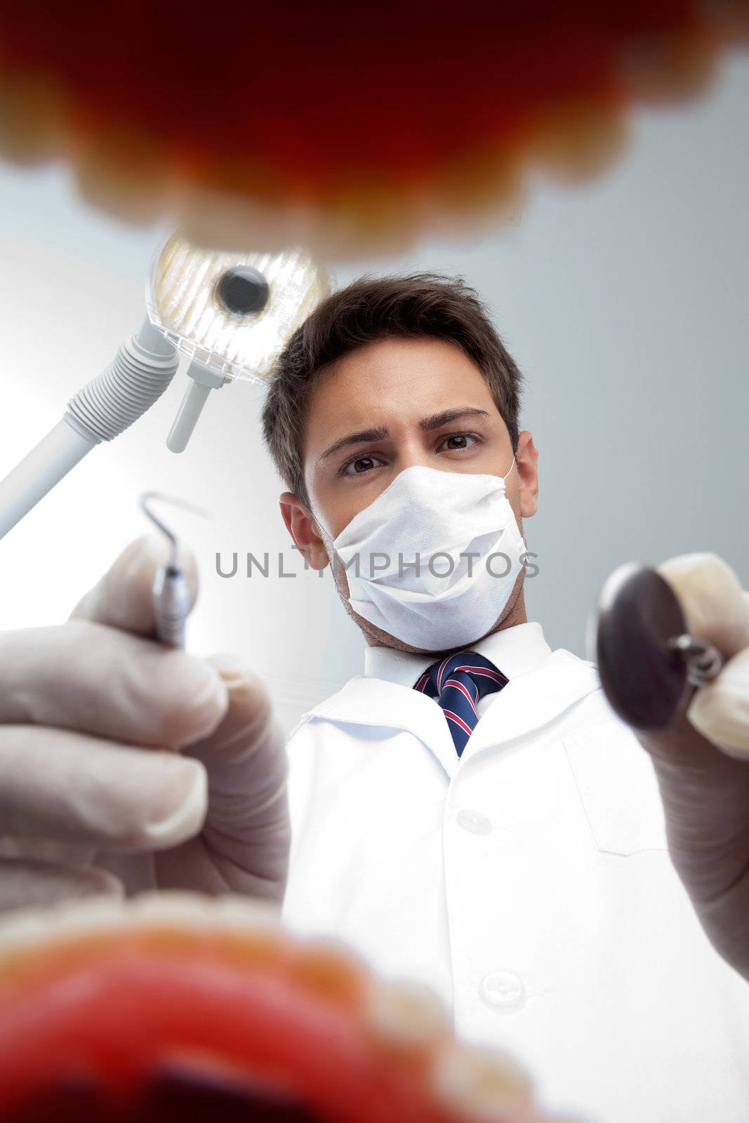 Portrait of young male dentist wearing surgical mask while examining patient's mouth