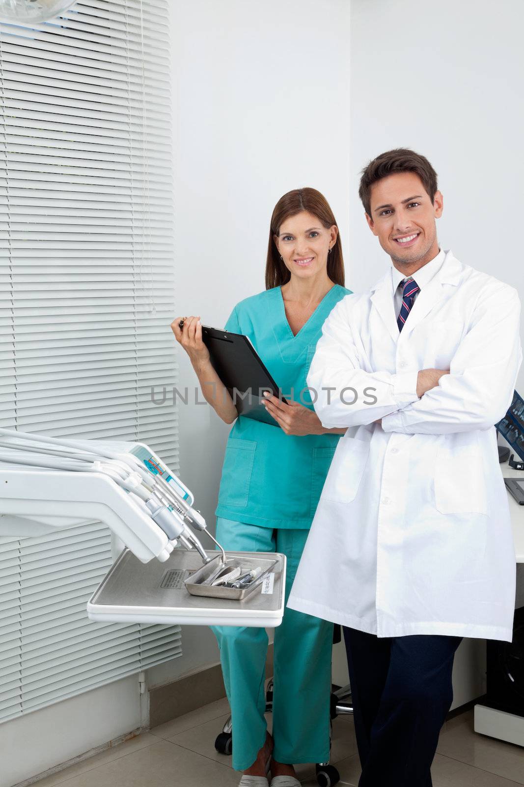 Portrait of young male dentist and assistant standing in dental clinic