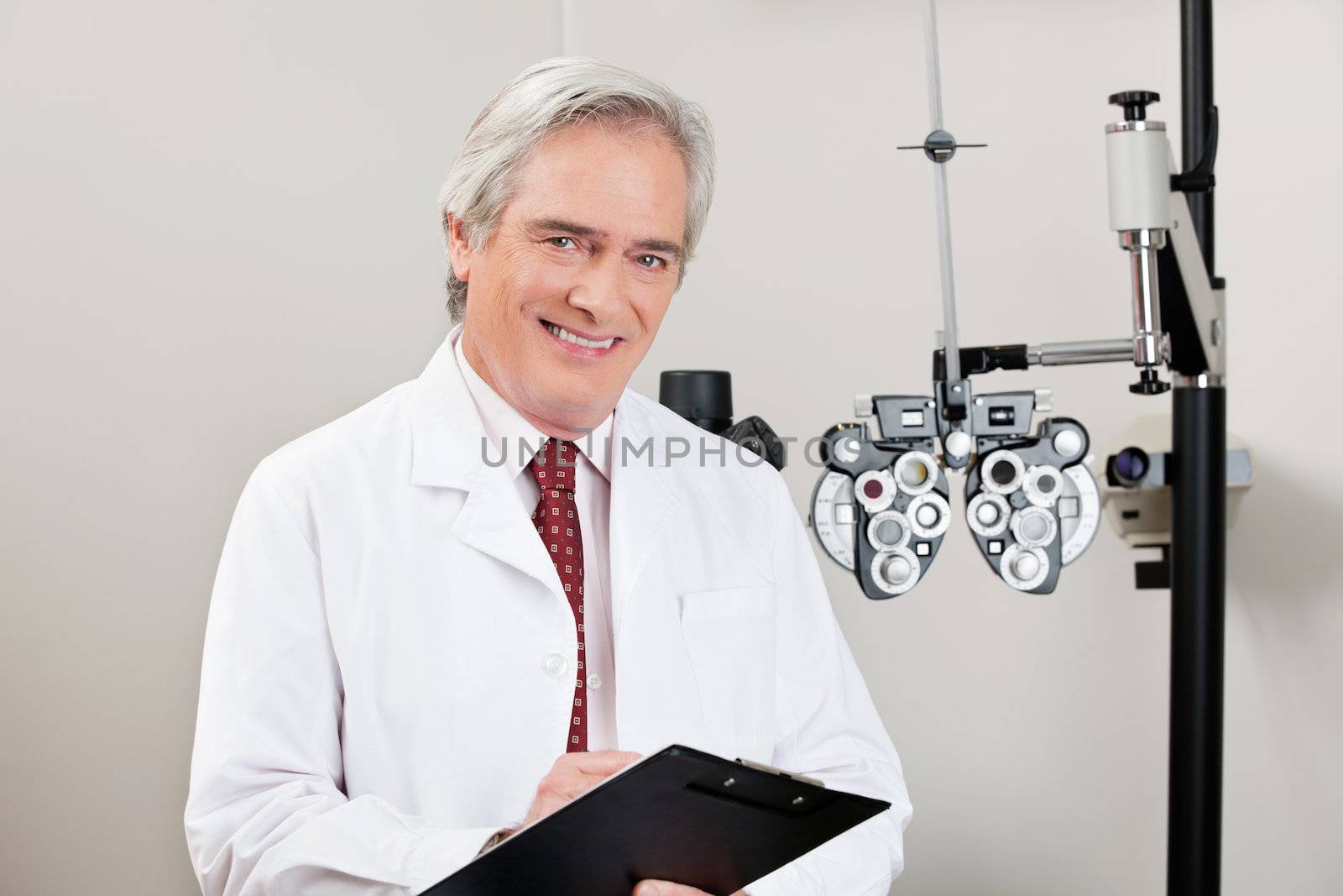 Experienced optometrist smiling with notepad in his clinic