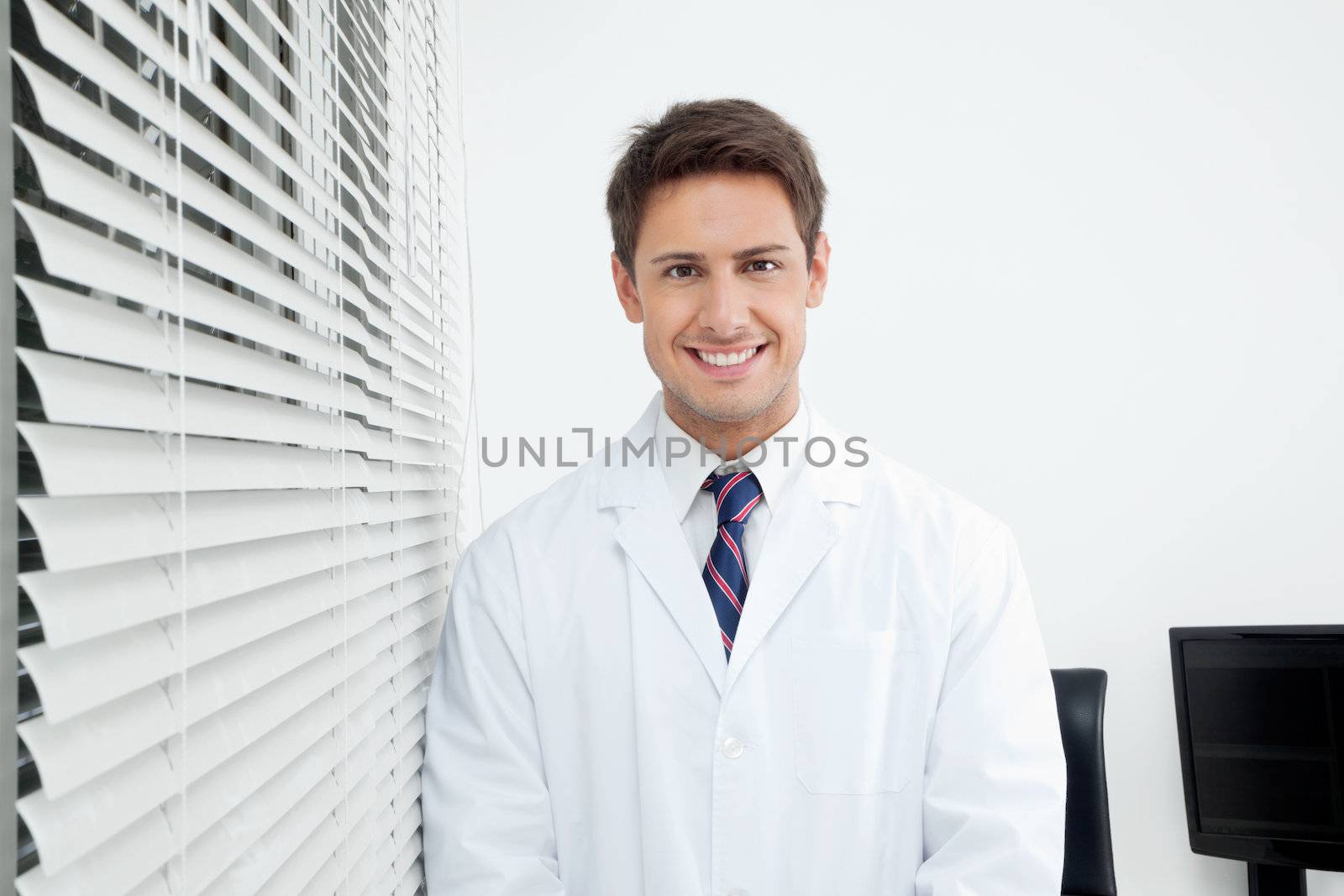 Happy Dentist Standing In Clinic by leaf