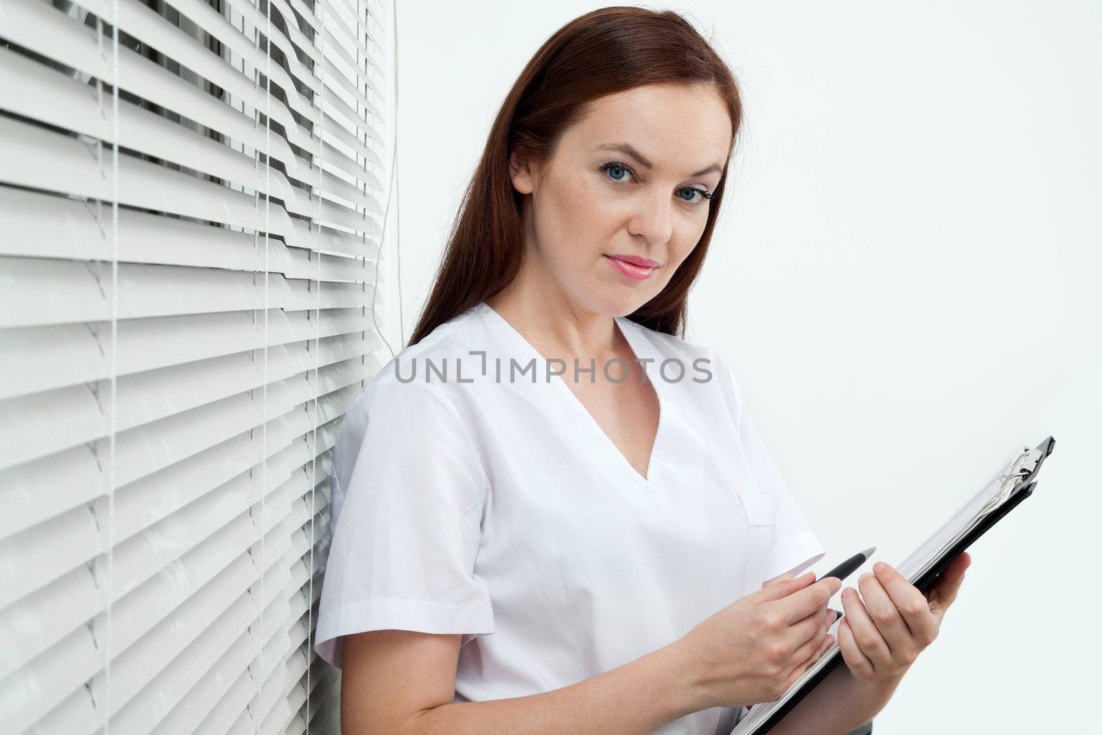 Portrait of confident female dentist holding clip board and pen in clinic