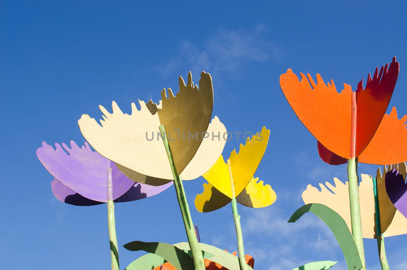 colorful stylized design decor tulips cut from plywood wood board against blue sky background.
