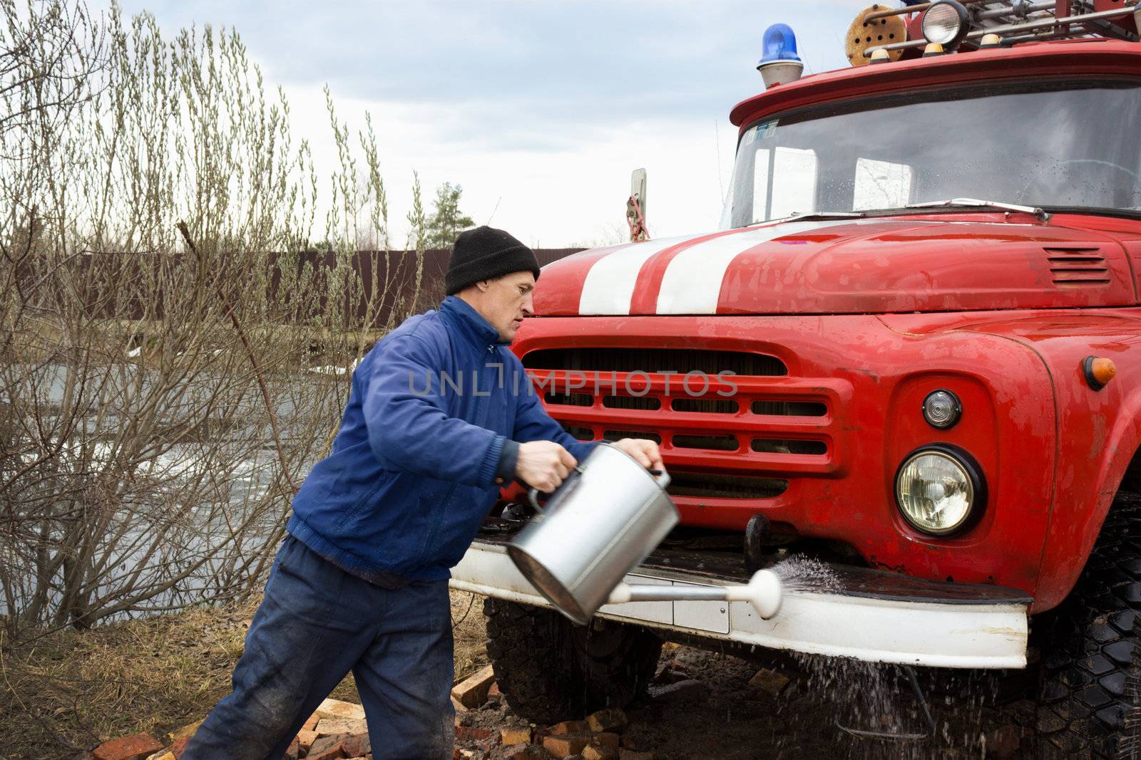 The driver of the water washes the old fire truck