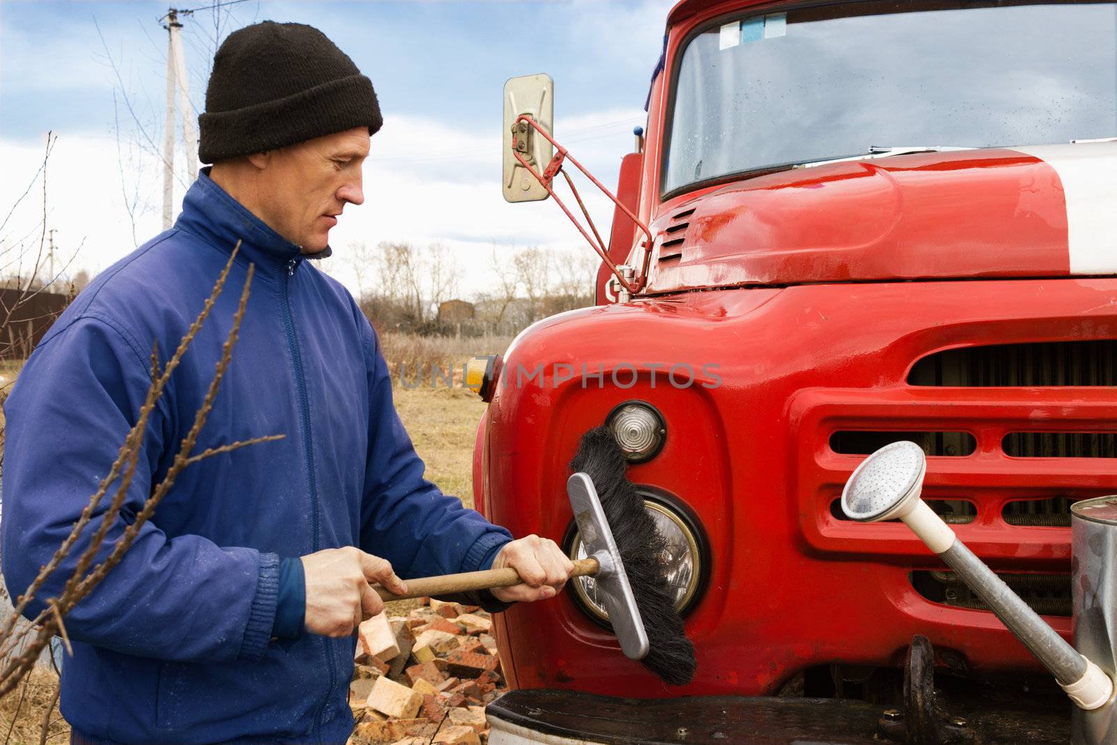 A man washes the old red fire truck