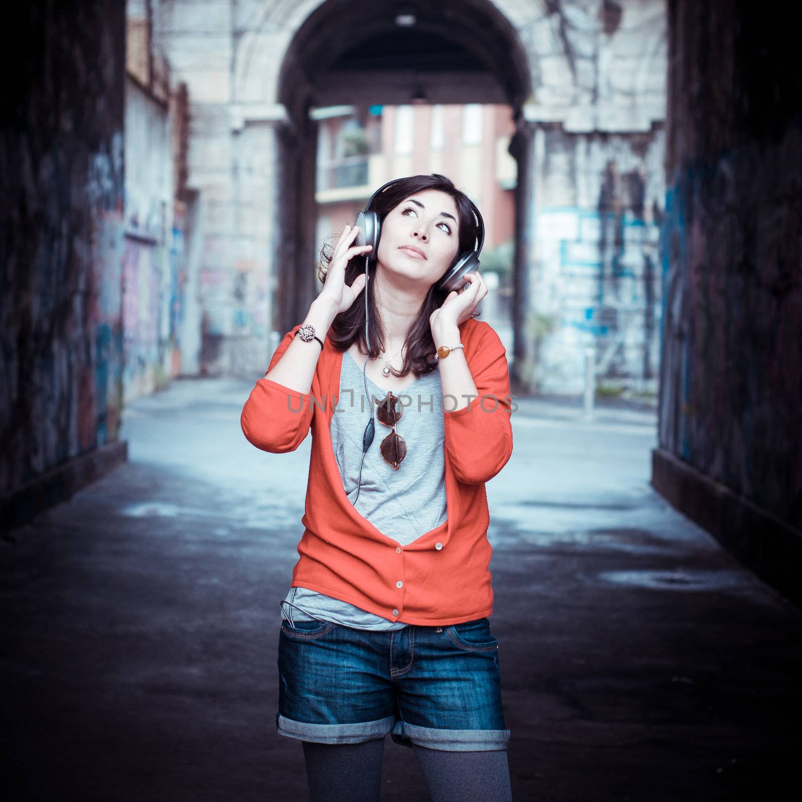 Beautiful stylish woman listening to music in the street 