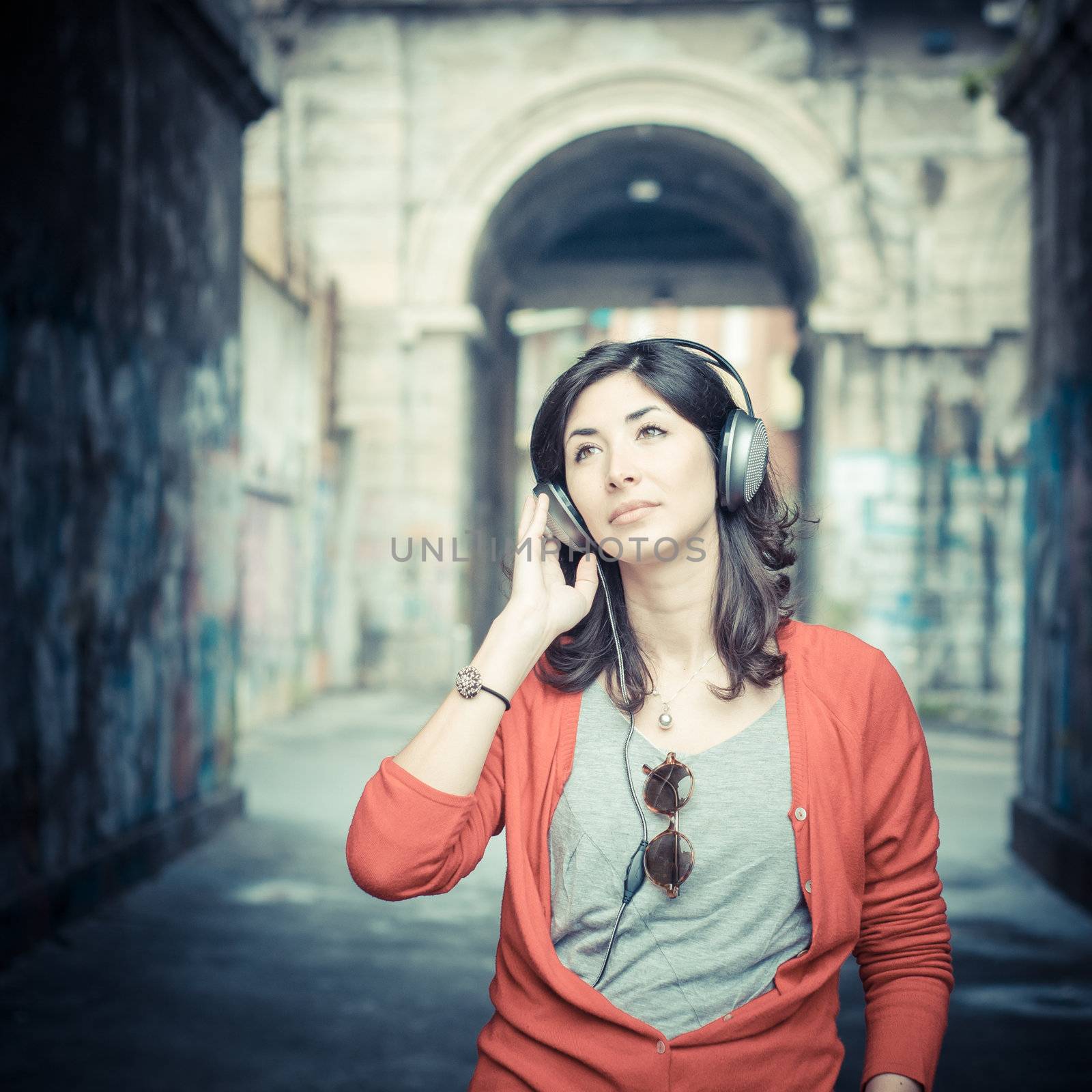 Beautiful stylish woman listening to music in the street 