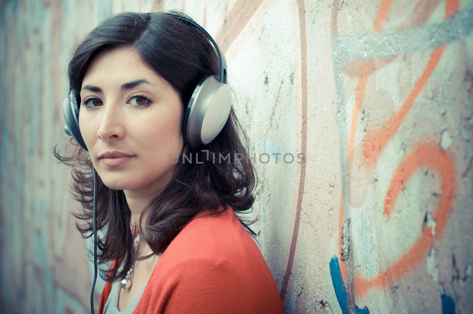 Beautiful stylish woman listening to music in the street 