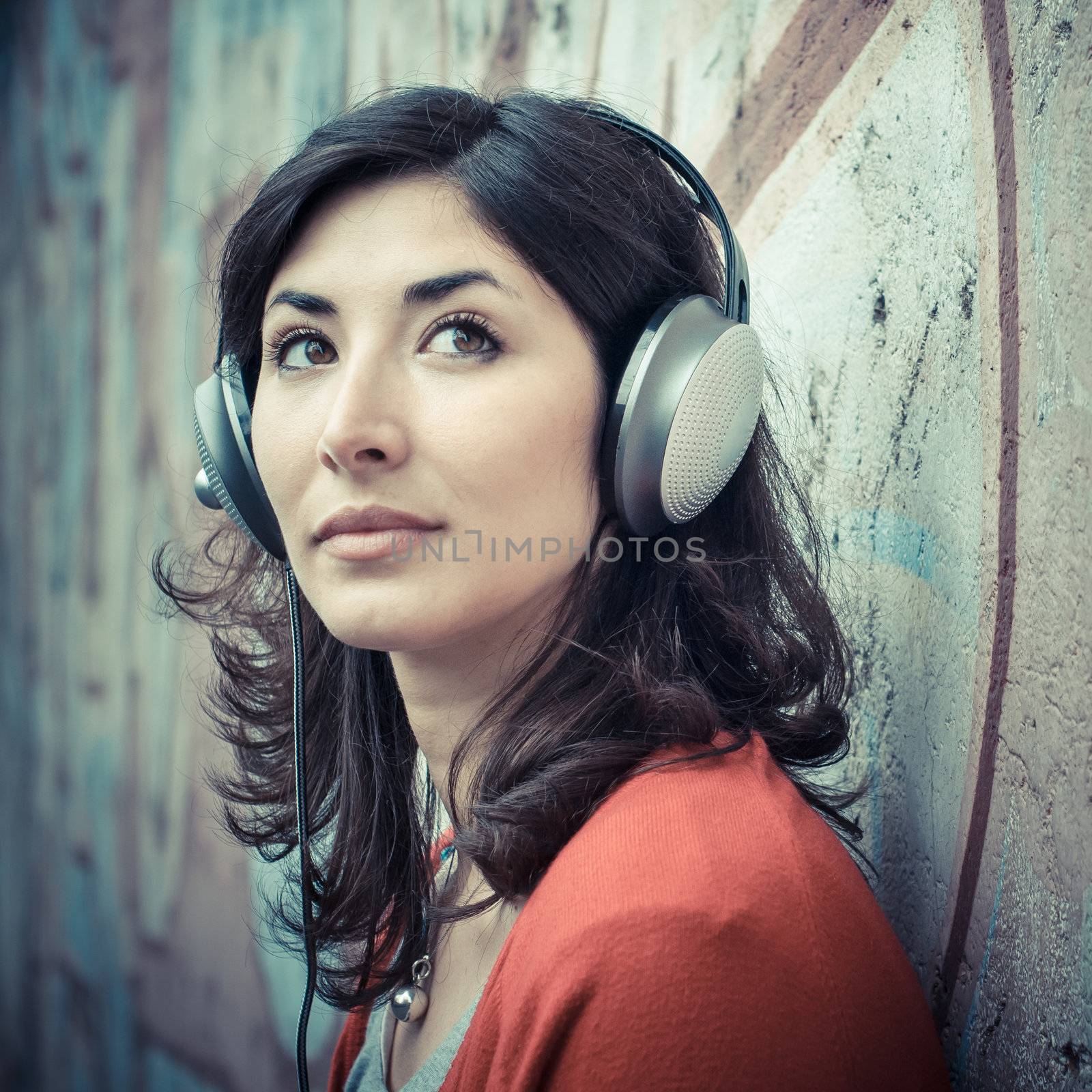 Beautiful stylish woman listening to music in the street 