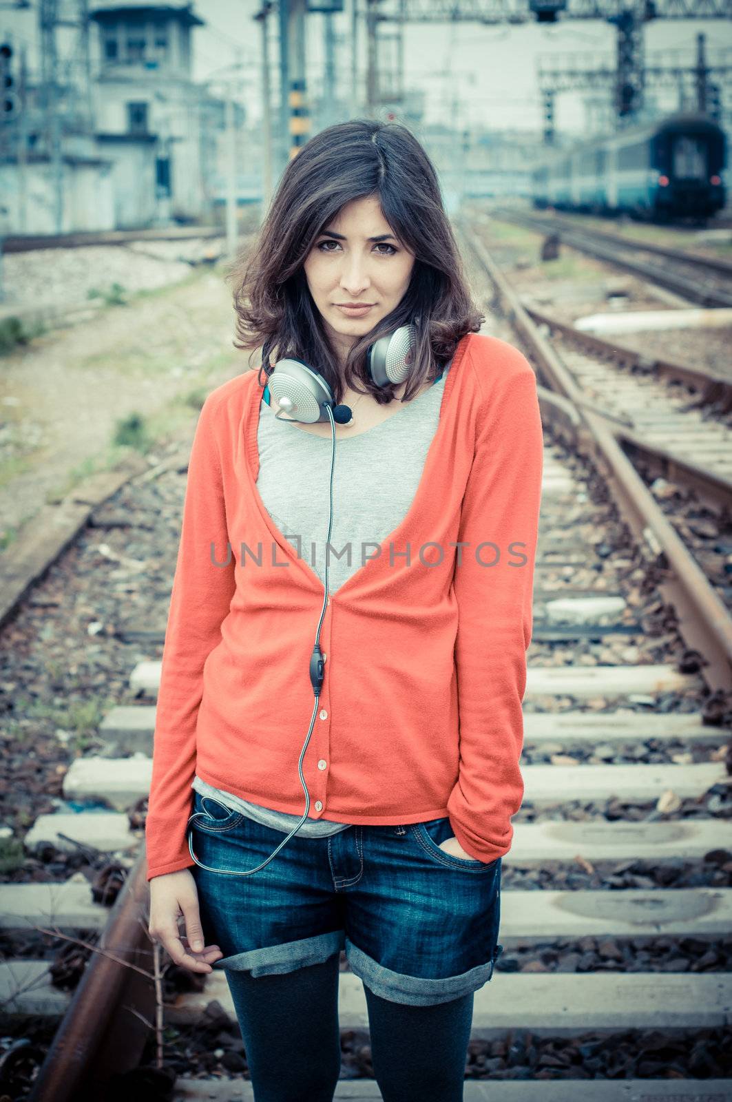 Beautiful stylish woman listening to music in railway