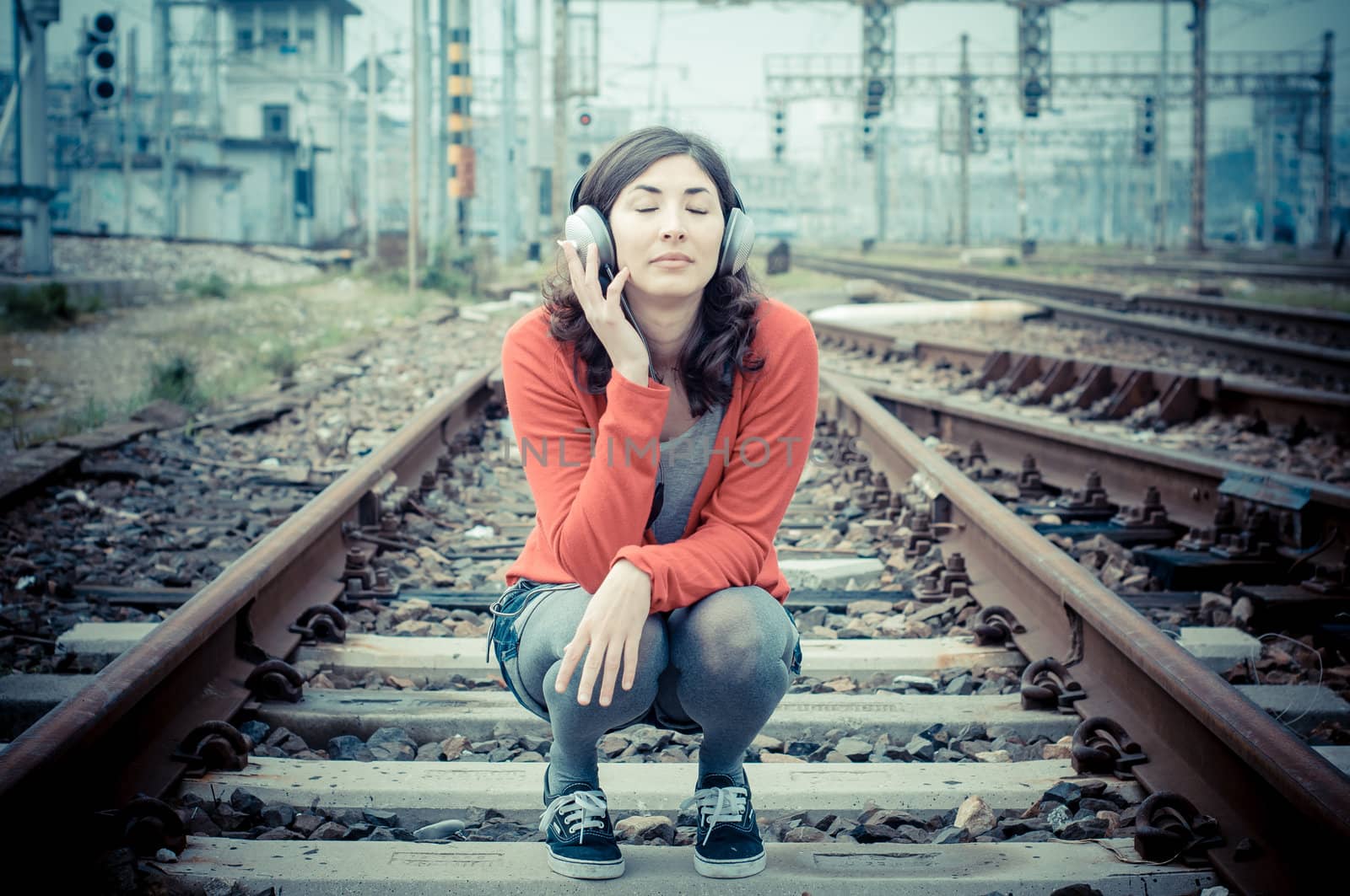 Beautiful stylish woman listening to music in railway
