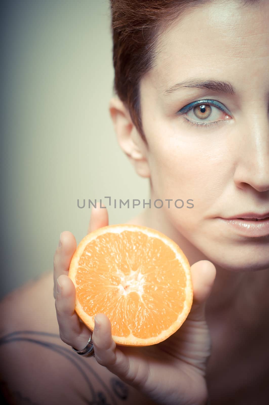 beautiful girl with short red hair and fruit on gray background