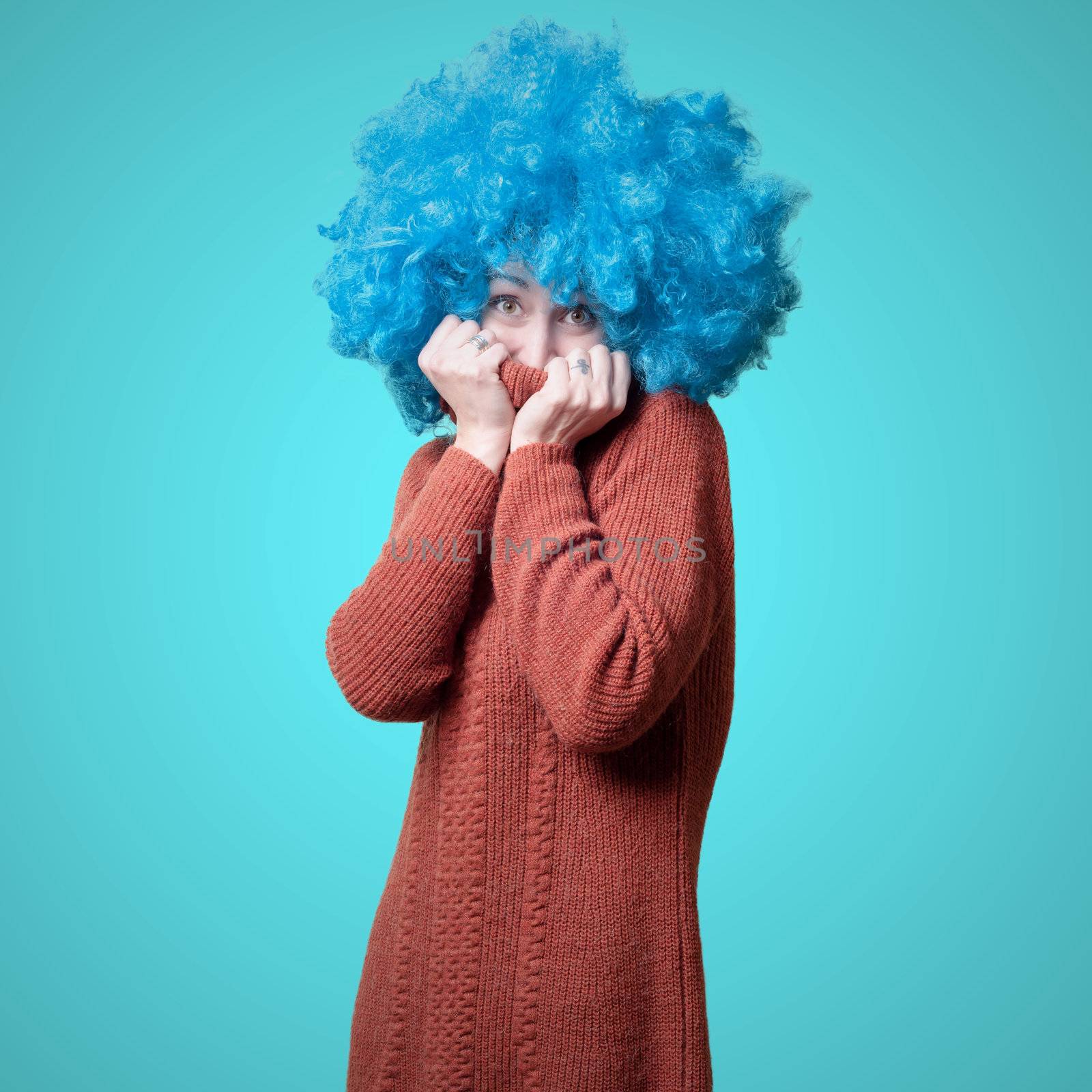 beautiful girl with curly blue wig and turtleneck on colorful background