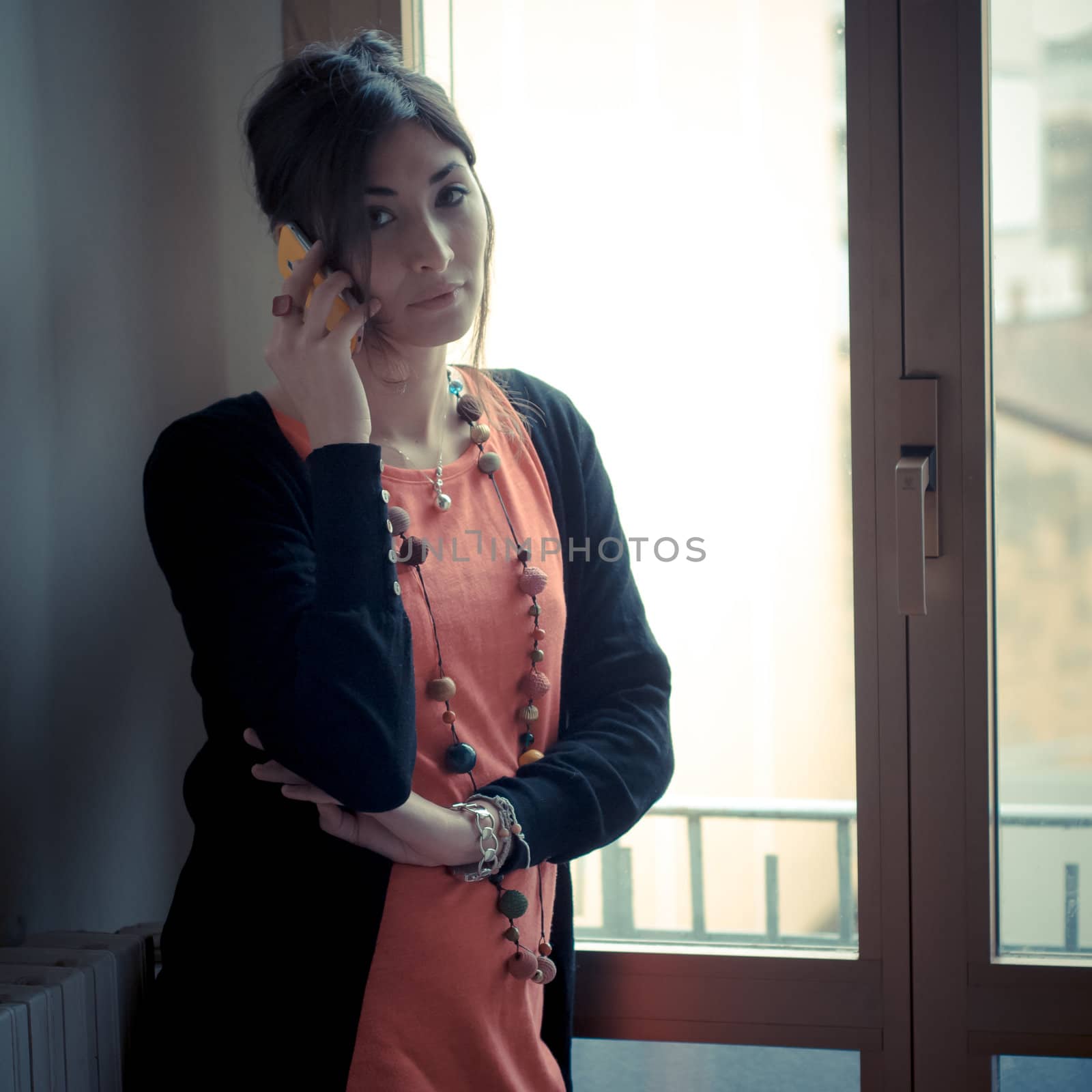 beautiful woman at home at the phone near window