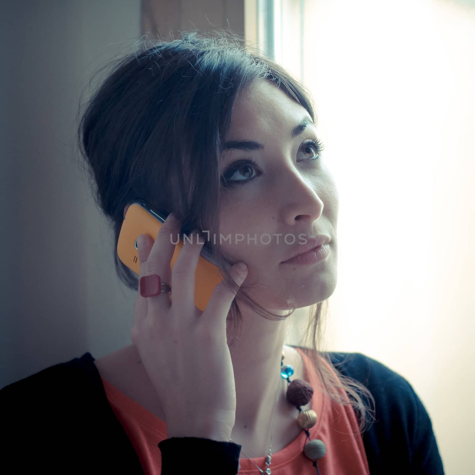 beautiful woman at home at the phone near window