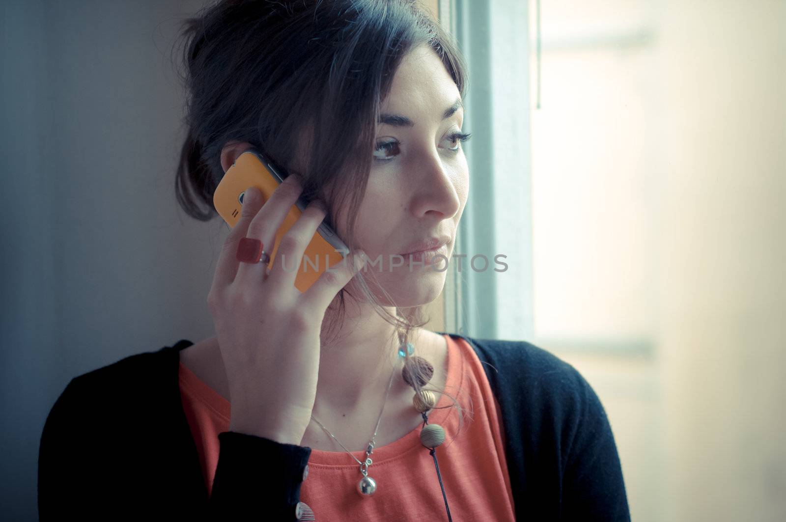 beautiful woman at home at the phone near window