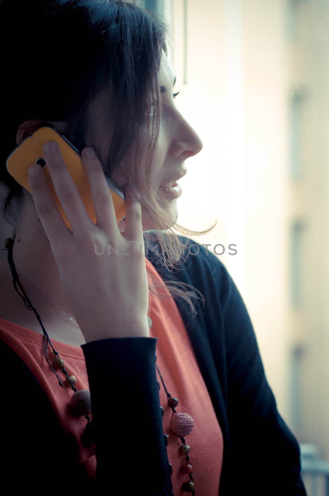 beautiful woman at home at the phone near window