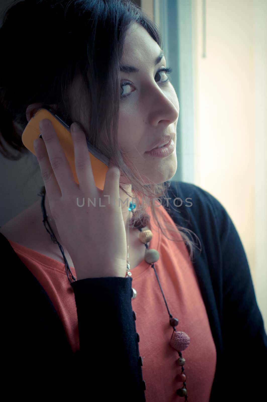 beautiful woman at home at the phone near window