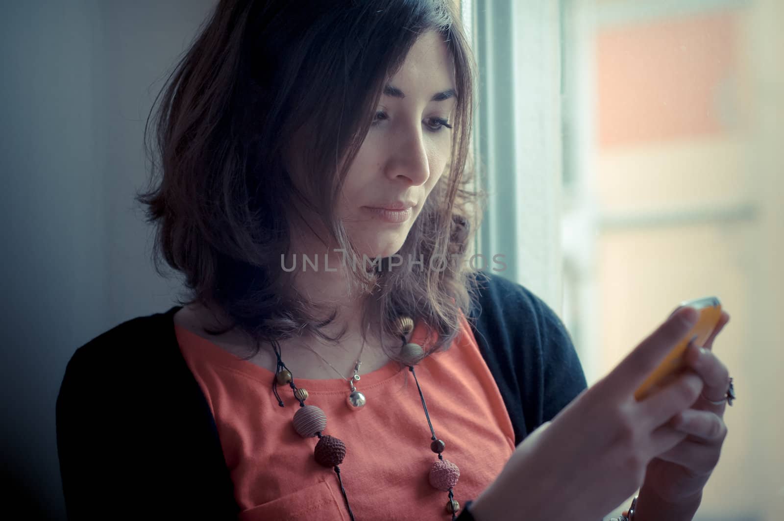 beautiful woman at home at the phone near window