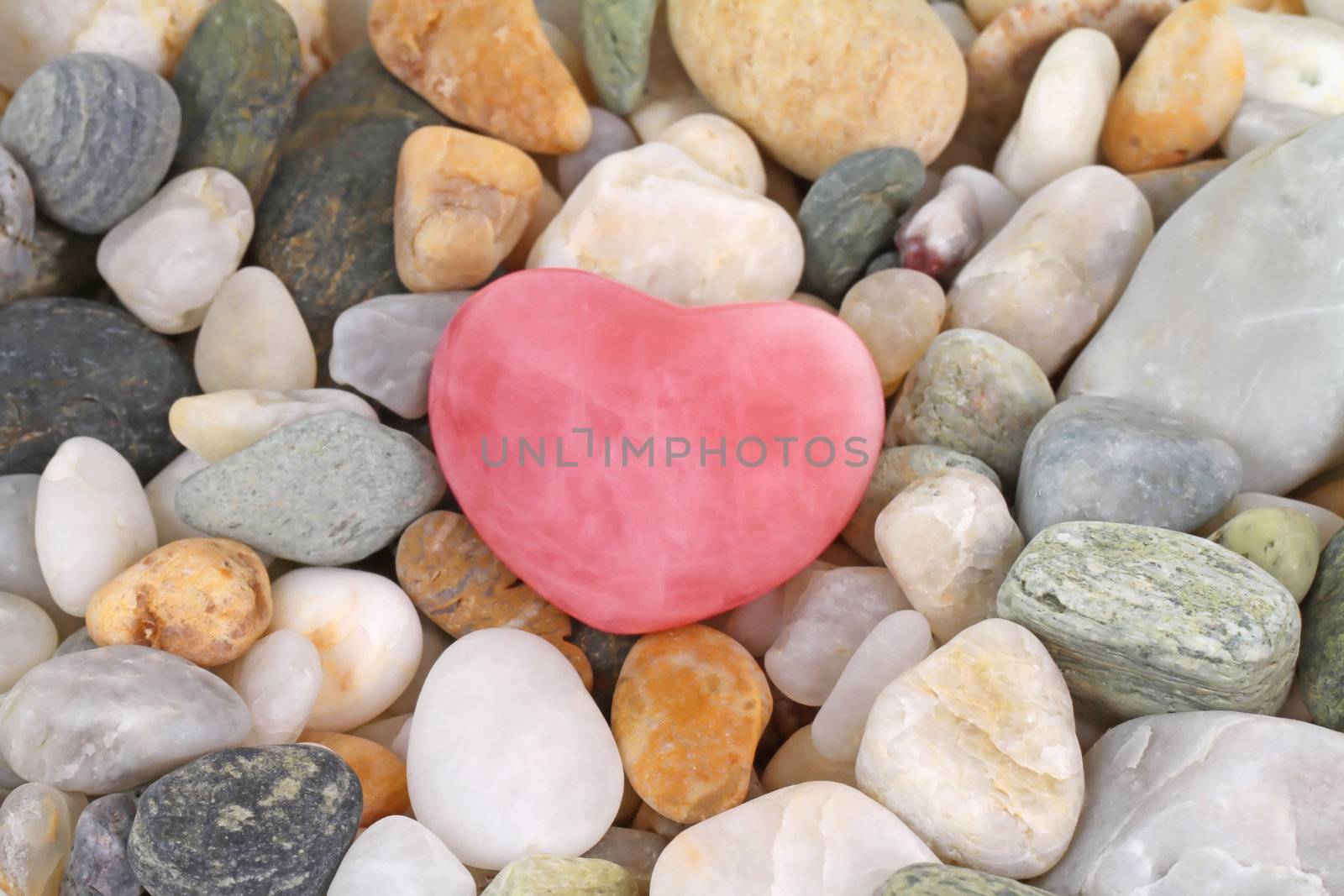 Beautiful rose quartz gem heart on pebbles
