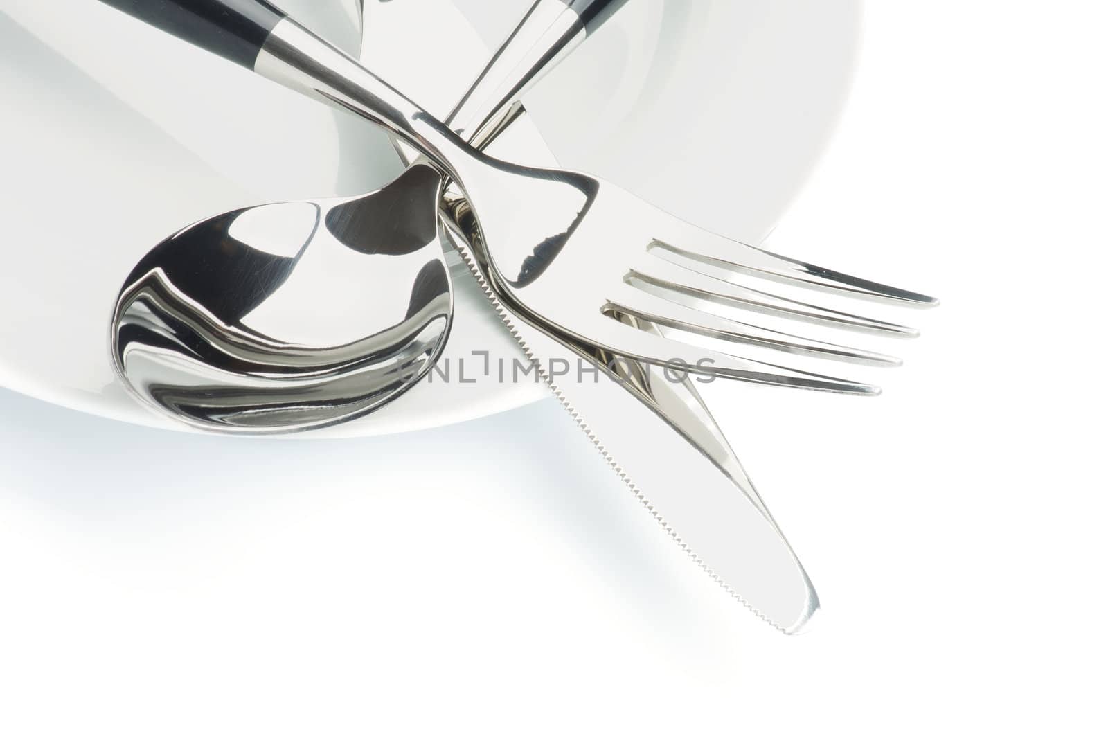Arrangement of Silverware with Table Knife, Spoon and on White Plate isolated on white background