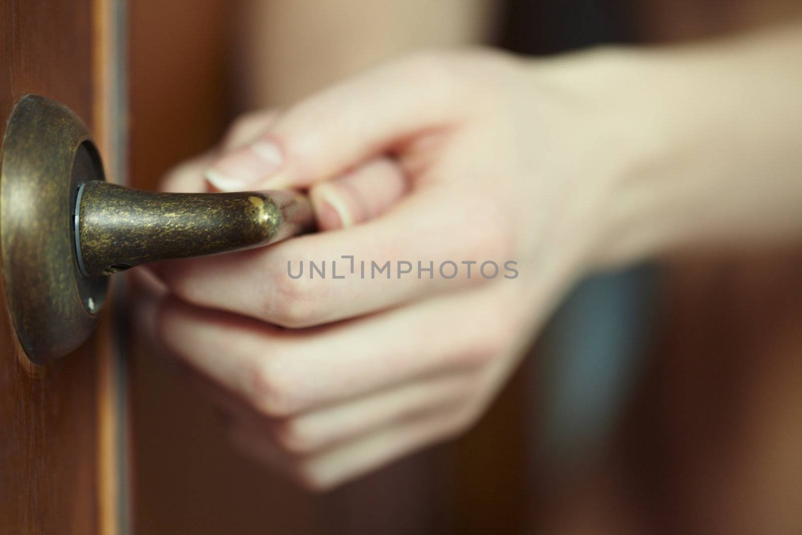 Close-up photo of the human hands holding door handle. Shallow depth of field added by the lens for natural view