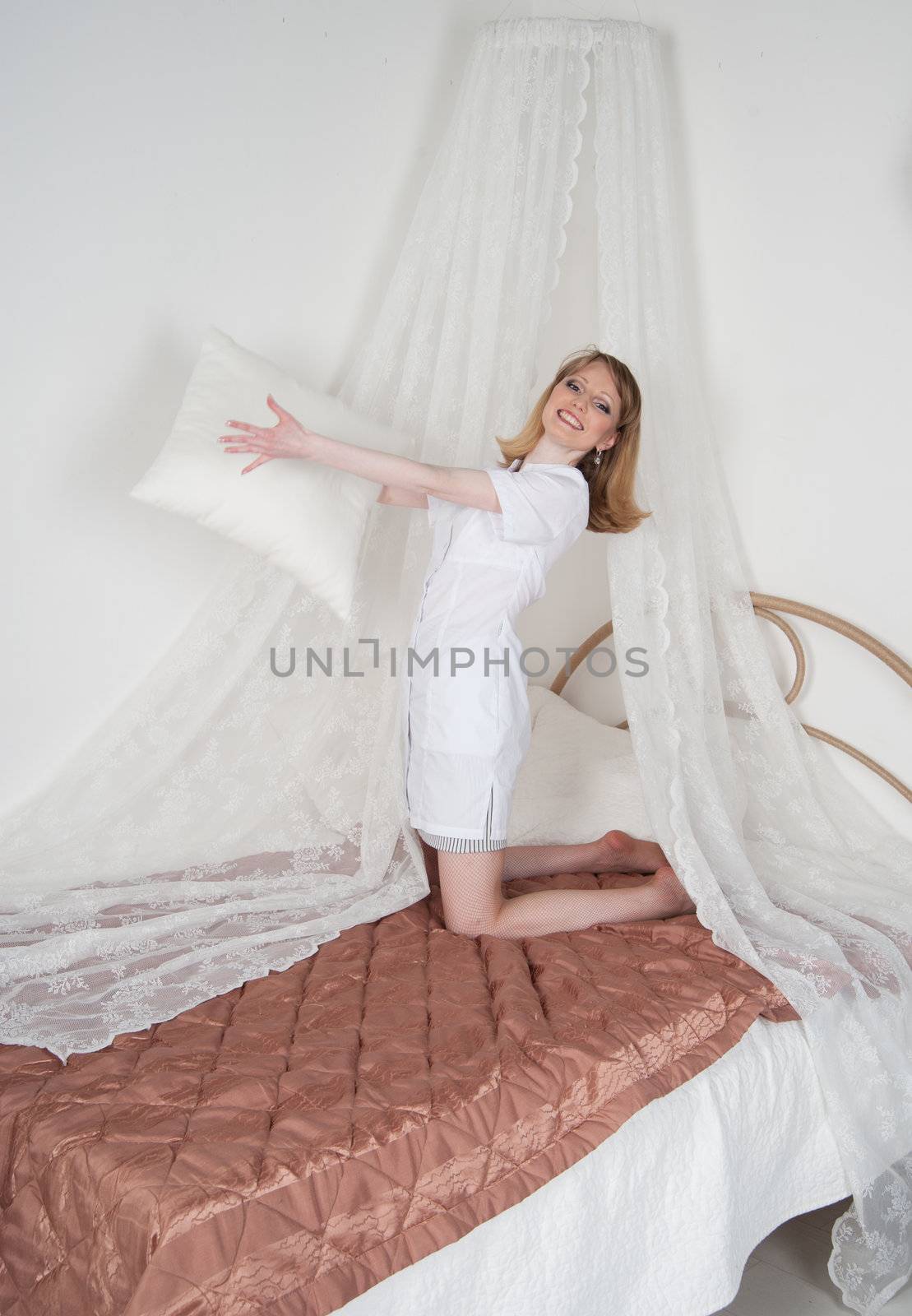 sexy woman doctor on the bed throwing pillows