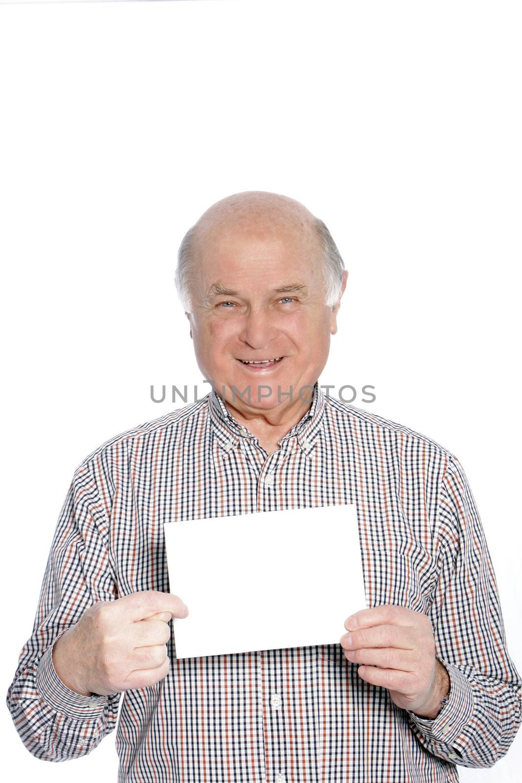 Senior man or pensioner with a lovely smile holding a blank card to his chest with copyspace for your text, isolated on white