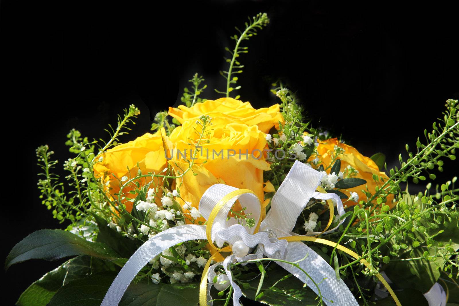 A bouquet of yellow flowers with a decorative white ribbon, close-up