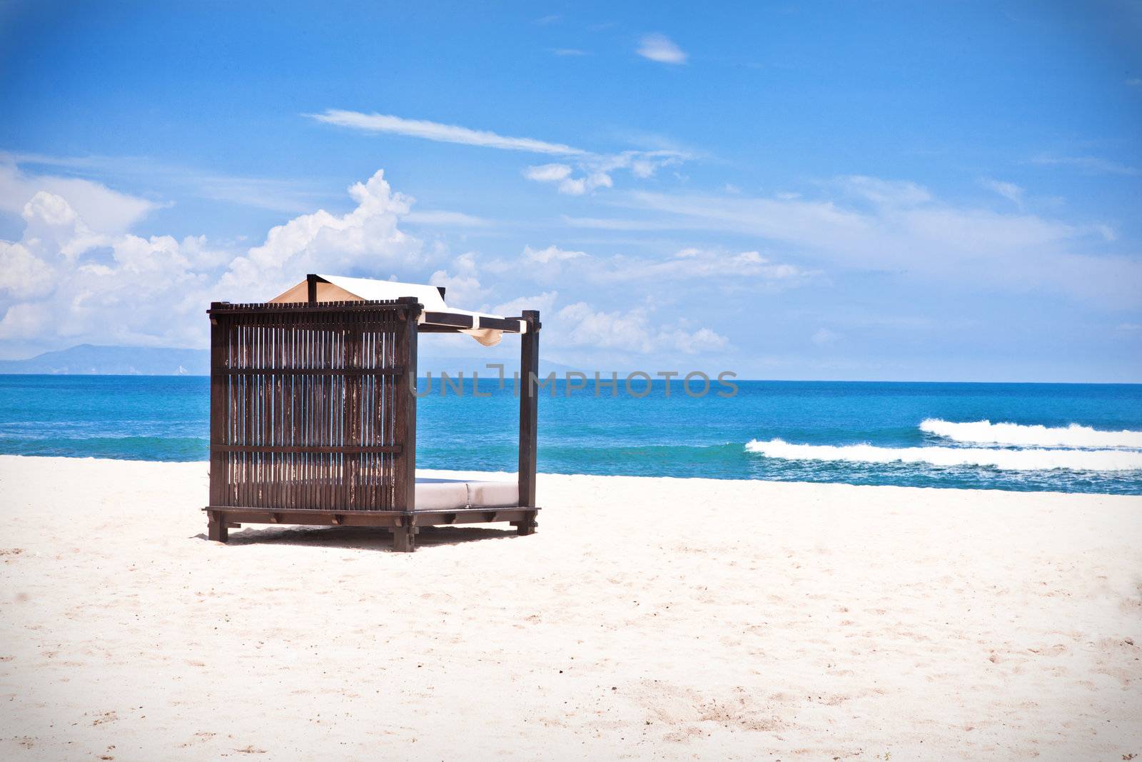 Beach bed with canopy on a beautiful tropical beach with golden sand overlooking the ocean