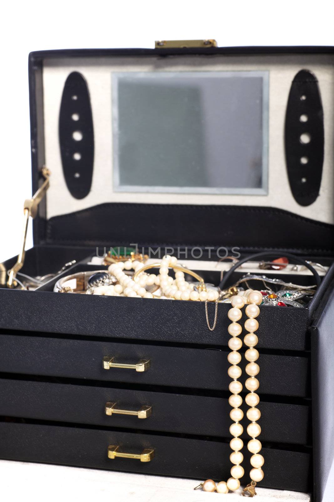 Open jewellery box with a pearl necklace hanging over the front and the top tray filled with assorted jewellery