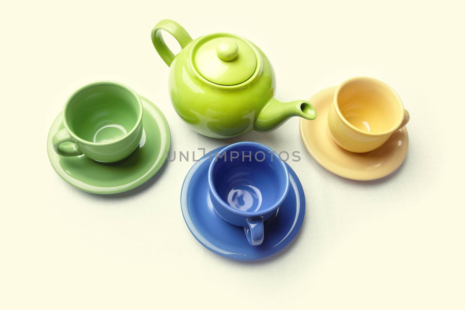 One teapot and three teacups on a textured background