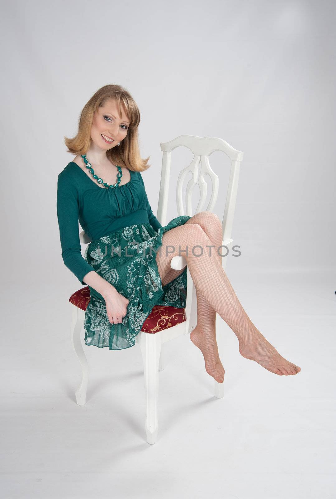 beautiful woman in a green dress sitting on a chair
