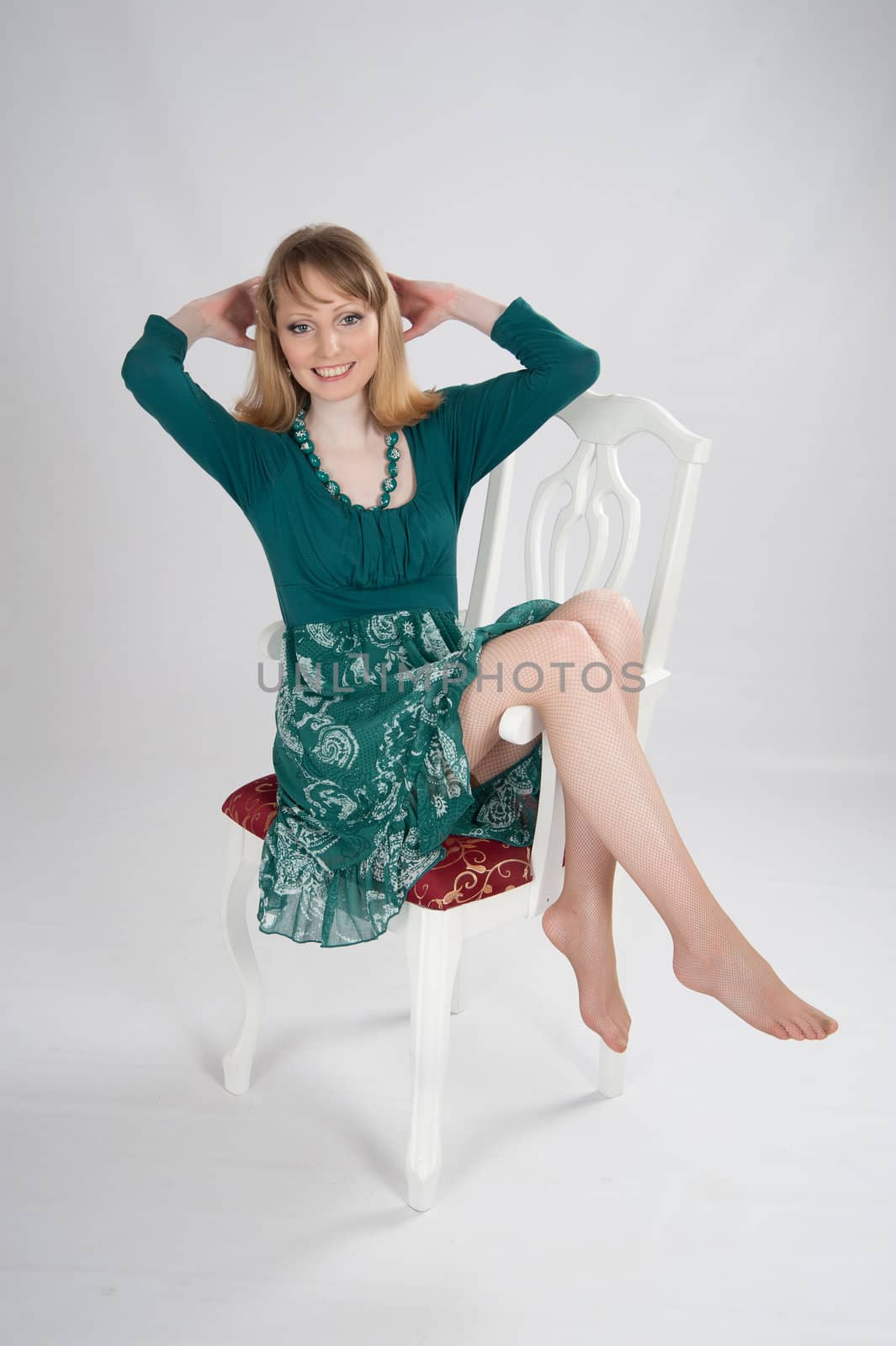 beautiful woman in a green dress sitting on a chair